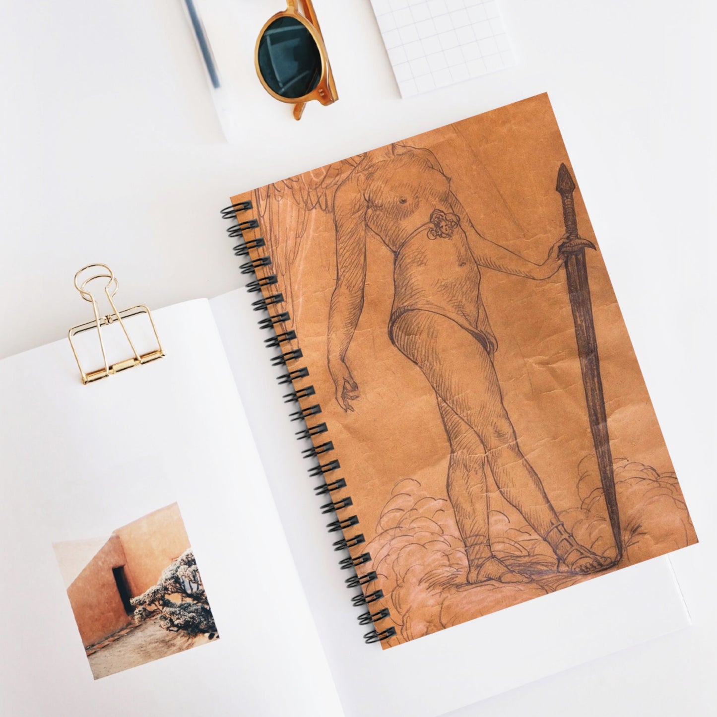 A drawing of an angel holding a sword. Woman breasts sword, beauty fashion. Spiral Bound Ruled Notebook with Printed Cover