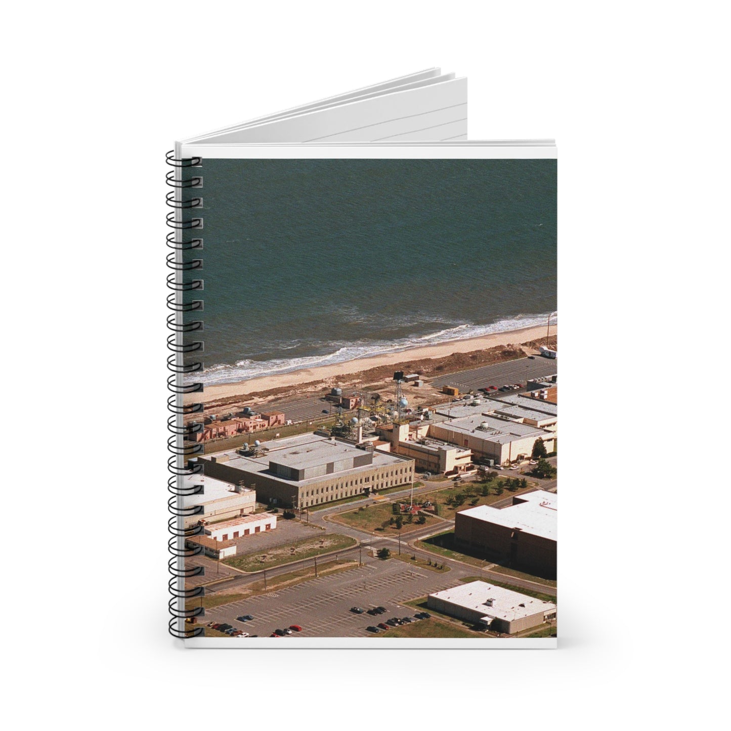 An aerial view of the Naval Surface Warfare Center testing building on the Dam Neck Naval Base. Along the beach are various types of gun mounts with their associated fire control radars atop the test building Spiral Bound Ruled Notebook with Printed Cover